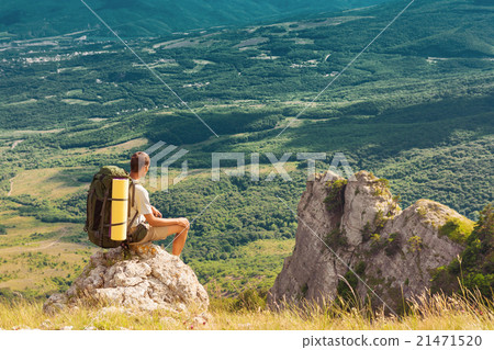 Backpacker sits on rock and looking at the valley 21471520