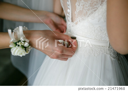 Bridesmaid is helping the bride to dress 21471968