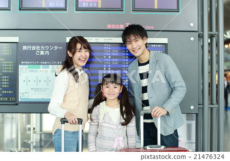 A family standing in front of the departure and arrival guide board 21476324