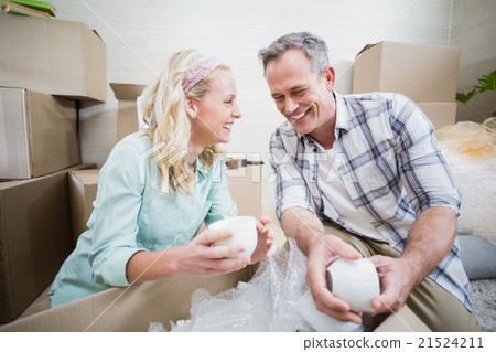 Smiling couple packing mug in a box Smiling couple packing mug in a box 21524211