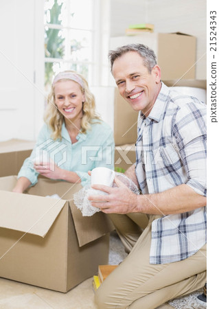 Smiling couple packing mug in a box Smiling couple packing mug in a box 21524343