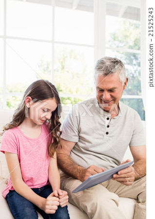 Smiling grandfather and granddaughter using tablet 21525243