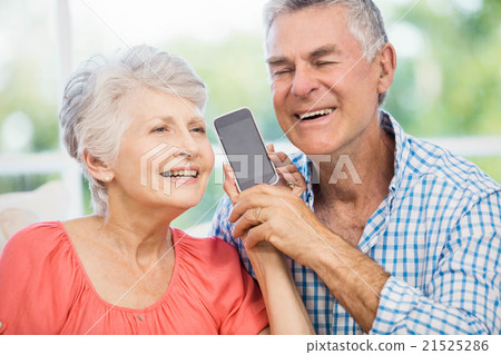 Happy senior couple listening to smartphone Happy senior couple listening to smartphone 21525286