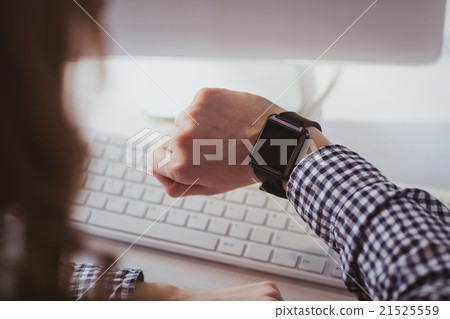 Over the shoulder view of businesswoman watching her smart watch 21525559
