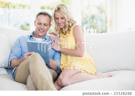 Happy couple using tablet on the sofa 21526288