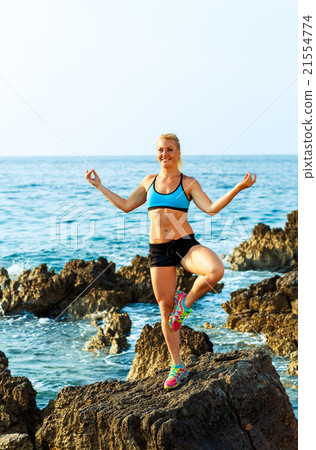 Happy athletic woman practicing yoga on the rocks by the sea Happy athletic woman practicing yoga on the rocks by the sea 21554774