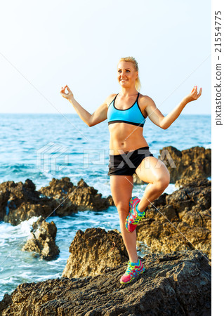 Happy athletic woman practicing yoga on the rocks by the sea Happy athletic woman practicing yoga on the rocks by the sea 21554775