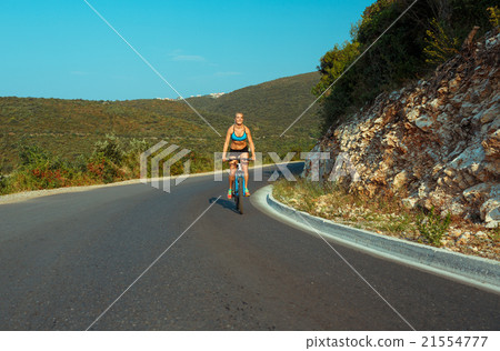 Woman cyclist riding a bike on a mountain road Woman cyclist riding a bike on a mountain road 21554777