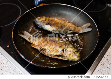 Fried fish in a frying pan on the cooker 21556344
