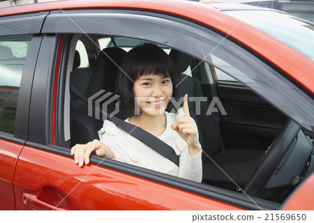 一位坐在駕駛座上，微笑著指著的年輕女士 21569650