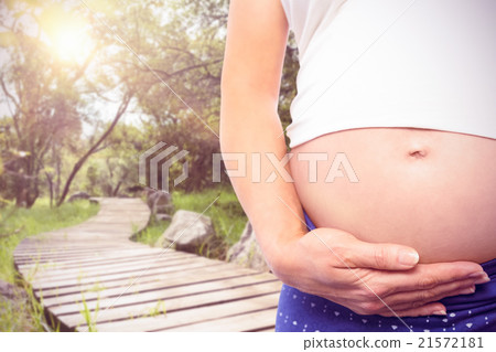 Composite image of pregnant woman holding baby shoes over bump 21572181