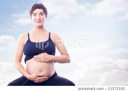 Composite image of portrait of happy pregnant woman holding belly 21572192