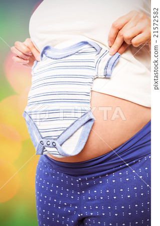 Composite image of pregnant woman holding baby clothes 21572582
