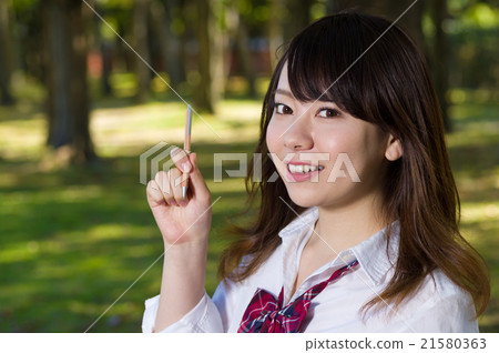 有微笑的一名婦女指向與一支筆的天空的與綠色後面女孩高中學生決議圖像 21580363