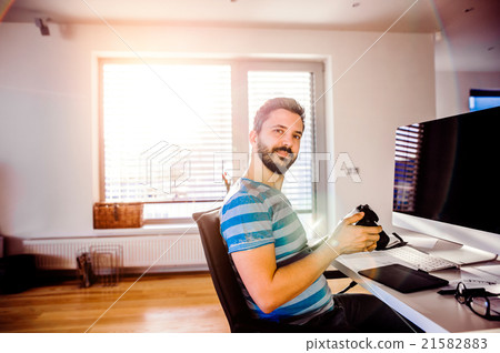 Man sitting at desk working from home holding Man sitting at desk working from home holding 21582883