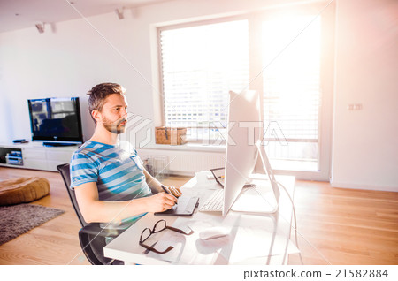 Man sitting at desk working from home on computer Man sitting at desk working from home on computer 21582884