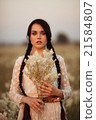 Young girl with long dark hair holding white flowers at the spring field. 21584807