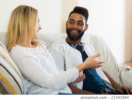 Young interracial couple chatting and laughing indoors Young interracial couple chatting and laughing indoors 21593904