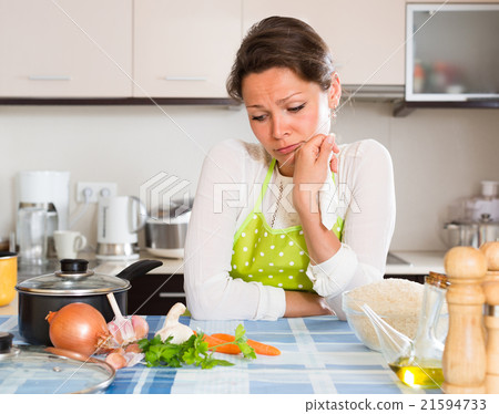 Sad woman cooking rice in the kitchen . 21594733