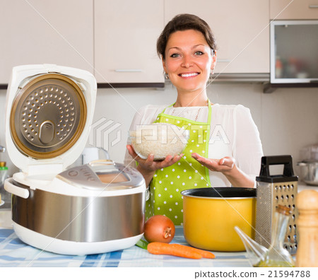 Woman cooking with multicooker at home. 21594788