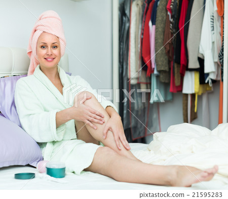 Attractive woman putting cream on legs Attractive woman putting cream on legs 21595283