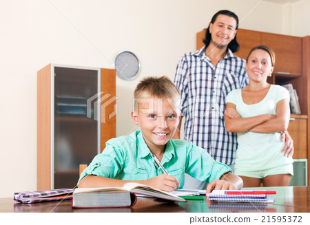parents watching their son doing homework 21595372