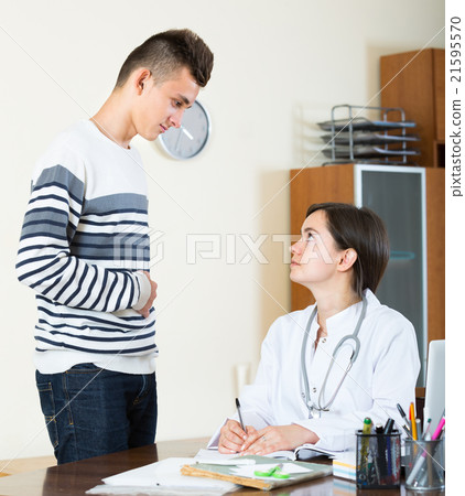 Teenager and doctor at desk in clinic. 21595570