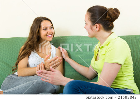 Two girls gossiping on sofa at home. Two girls gossiping on sofa at home. 21595842
