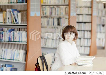 A woman reading a book in a library A woman reading a book in a library 21596463