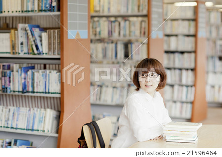 A woman reading a book in a library A woman reading a book in a library 21596464