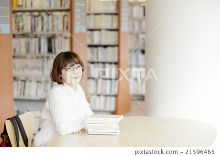 A woman reading a book in a library A woman reading a book in a library 21596465