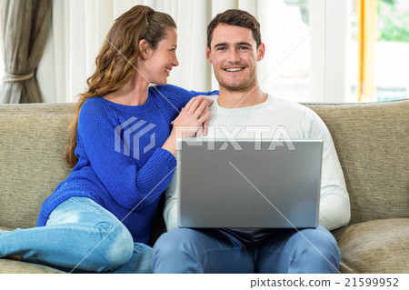 Young couple smiling face to face on sofa and using laptop Young couple smiling face to face on sofa and using laptop 21599952