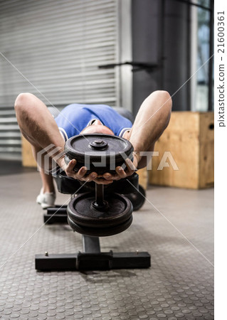 Muscular man on bench lifting dumbbell Muscular man on bench lifting dumbbell 21600361