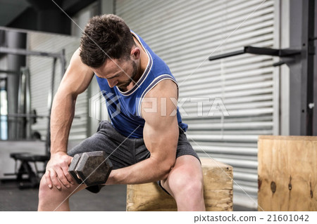 Muscular man lifting dumbbell on wooden block 21601042
