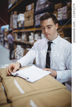 Warehouse manager looking at clipboard 21601274