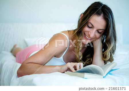 smiling woman reading a book in bed 21601371