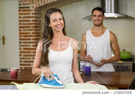 Portrait of woman ironing a shirt in kitchen Portrait of woman ironing a shirt in kitchen 21601508