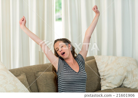 Young woman yawning and stretching her hands 21601906