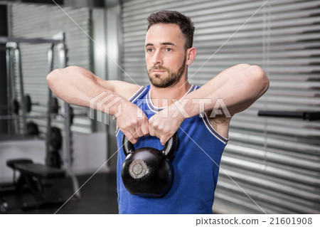 Muscular man lifting heavy kettlebell 21601908