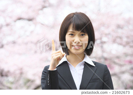 A woman with a suit pointing to a cherry blossom background 21602673
