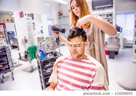 Professional hairdresser drying hair to her 21609045
