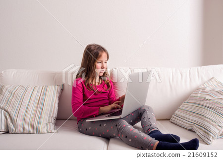 Girl at home sitting on sofa, playing with laptop Girl at home sitting on sofa, playing with laptop 21609152