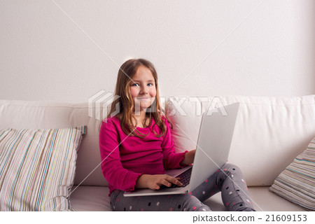Girl at home sitting on sofa, playing with laptop Girl at home sitting on sofa, playing with laptop 21609153