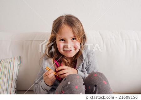Girl at home sitting on sofa, eating breadsticks Girl at home sitting on sofa, eating breadsticks 21609156