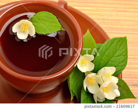 Tea in cup with jasmine flower on the wood Tea in cup with jasmine flower on the wood 21609617