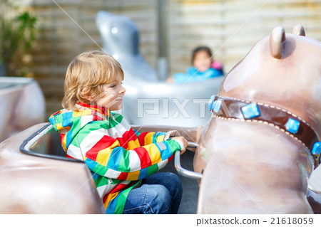 Little kid boy on carousel in amusement park 21618059