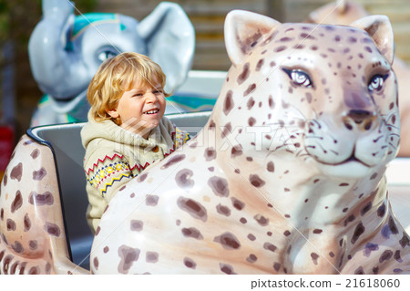 Little kid boy on carousel in amusement park 21618060
