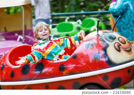 Little kid boy on carousel in amusement park 21618080