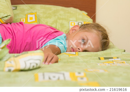 Six-year girl lying across the bed, trying to sleep Six-year girl lying across the bed, trying to sleep 21619616
