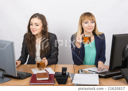 Two office girl working at computers in the hands of tea Two office girl working at computers in the hands of tea 21620817